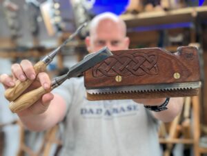 James Wright holding a hand carved kerfing plane and 2 chisels.